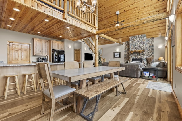 dining room featuring a fireplace, recessed lighting, light wood-type flooring, wooden ceiling, and stairs