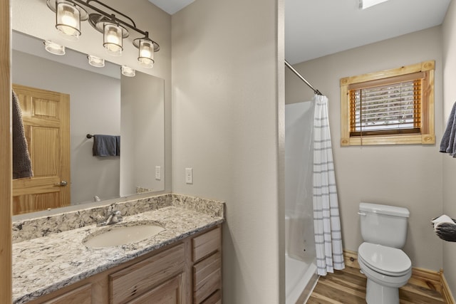 bathroom with baseboards, toilet, wood finished floors, curtained shower, and vanity