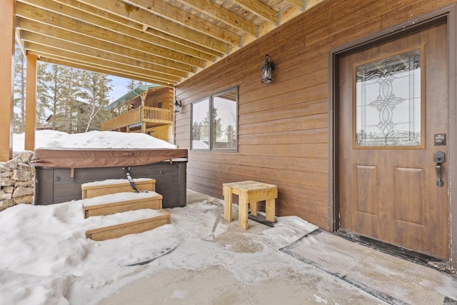 view of exterior entry with a hot tub and a balcony