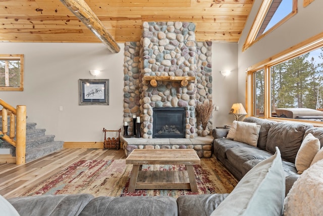 living room featuring beam ceiling, a fireplace, stairway, wood finished floors, and wooden ceiling