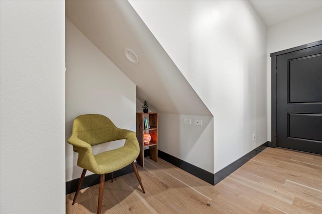 living area featuring vaulted ceiling and light hardwood / wood-style flooring