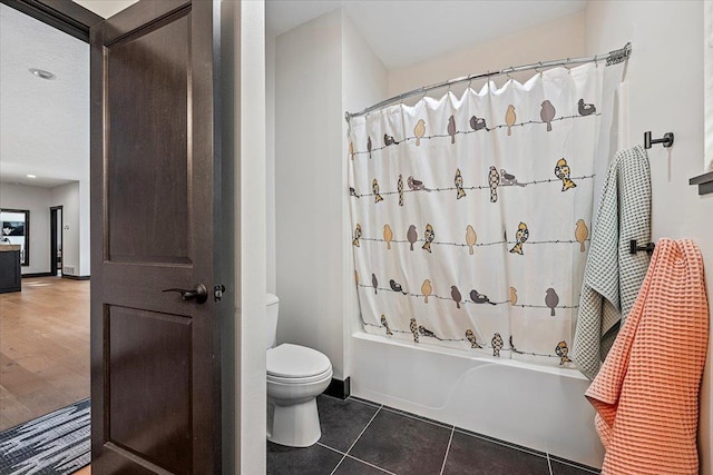 bathroom featuring shower / tub combo with curtain, tile patterned flooring, and toilet