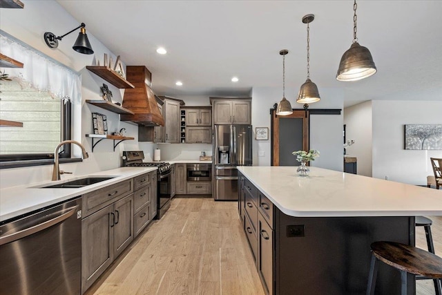 kitchen with sink, a breakfast bar area, appliances with stainless steel finishes, pendant lighting, and a large island