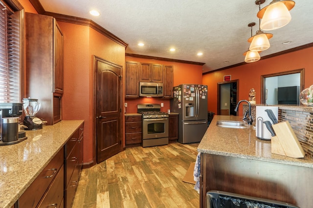 kitchen featuring pendant lighting, sink, stainless steel appliances, and light stone countertops