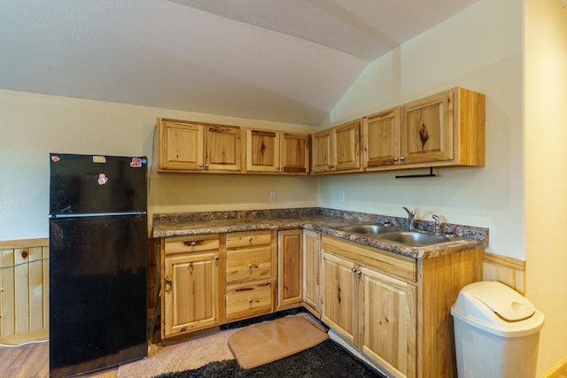 kitchen featuring black fridge, vaulted ceiling, and sink