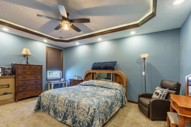 carpeted bedroom featuring a textured ceiling, ceiling fan, and a tray ceiling