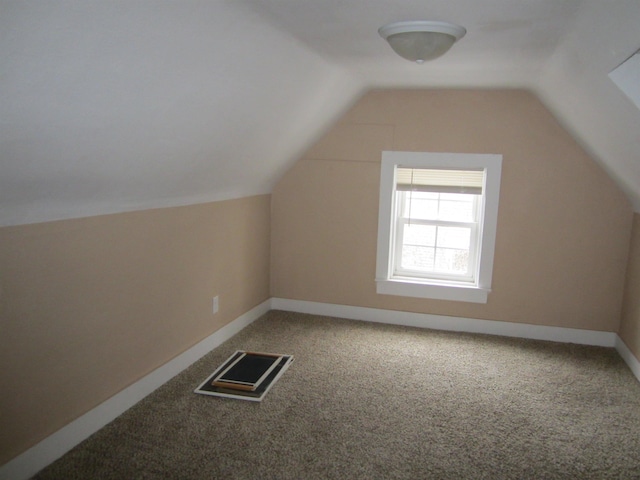 additional living space featuring vaulted ceiling and carpet flooring