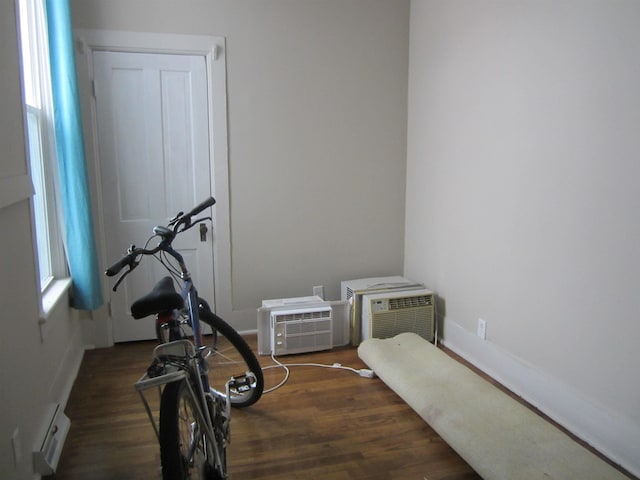 exercise room with a healthy amount of sunlight, dark hardwood / wood-style floors, and an AC wall unit