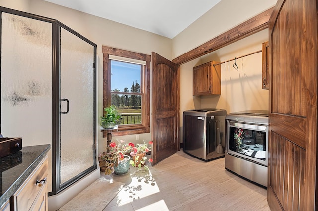 clothes washing area featuring light hardwood / wood-style flooring, cabinets, and washing machine and clothes dryer