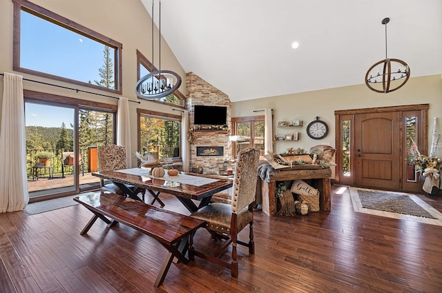 dining area featuring a fireplace, dark hardwood / wood-style floors, high vaulted ceiling, and a notable chandelier