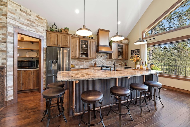 kitchen featuring hanging light fixtures, premium range hood, appliances with stainless steel finishes, and light stone counters