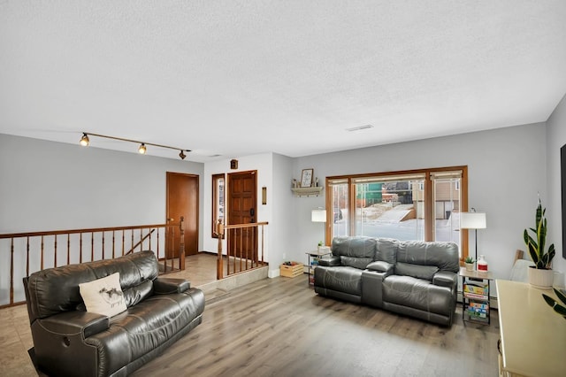 living room with track lighting, light hardwood / wood-style floors, and a textured ceiling