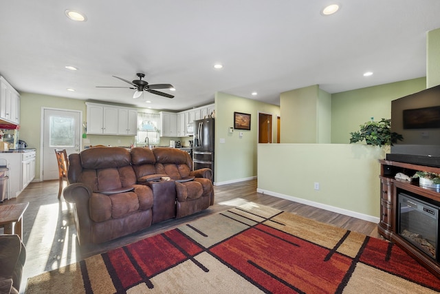 living room featuring ceiling fan, sink, and light hardwood / wood-style flooring