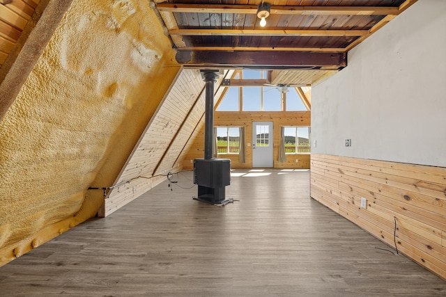 interior space featuring beamed ceiling, a wood stove, wooden walls, and dark hardwood / wood-style floors