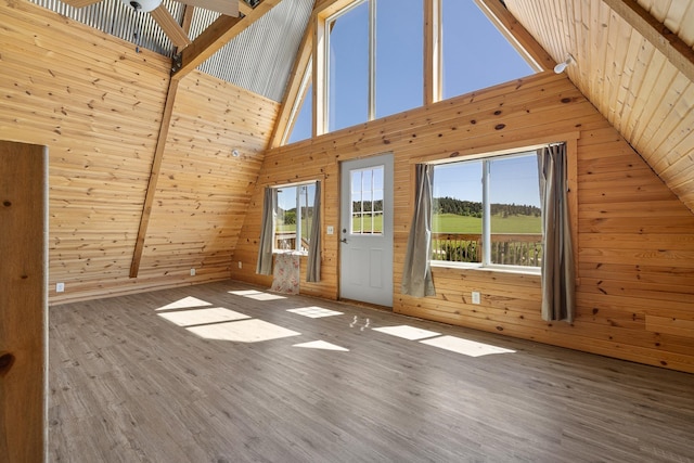 interior space with high vaulted ceiling, wooden walls, and hardwood / wood-style floors