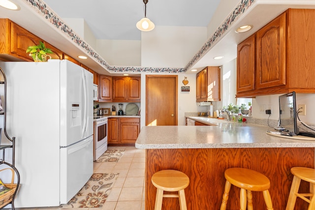 kitchen featuring light tile patterned flooring, decorative light fixtures, a kitchen bar, kitchen peninsula, and white appliances