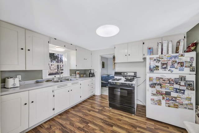 kitchen featuring sink, dark wood-type flooring, white refrigerator, gas stove, and white cabinets