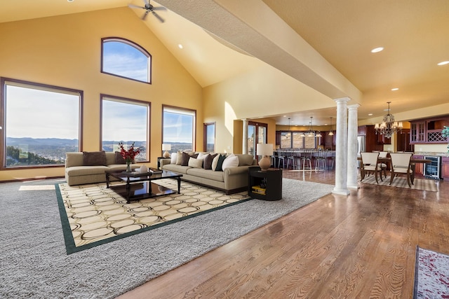 living room featuring wine cooler, ornate columns, high vaulted ceiling, a mountain view, and hardwood / wood-style flooring