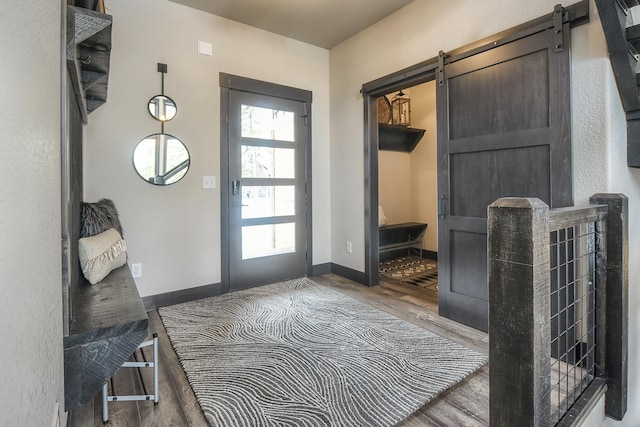 mudroom featuring a barn door, wood finished floors, and baseboards