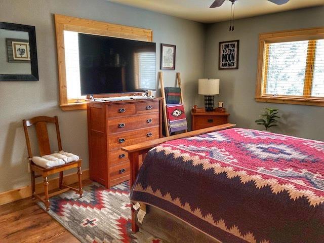 bedroom with a ceiling fan, baseboards, and wood finished floors