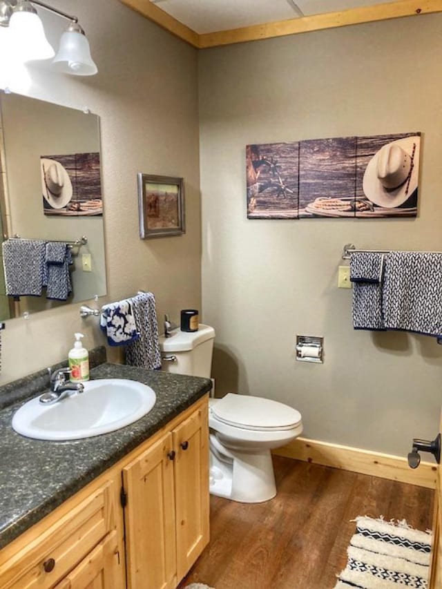 bathroom with toilet, baseboards, wood finished floors, and vanity