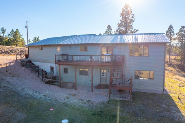 rear view of property with a deck, stairway, and metal roof