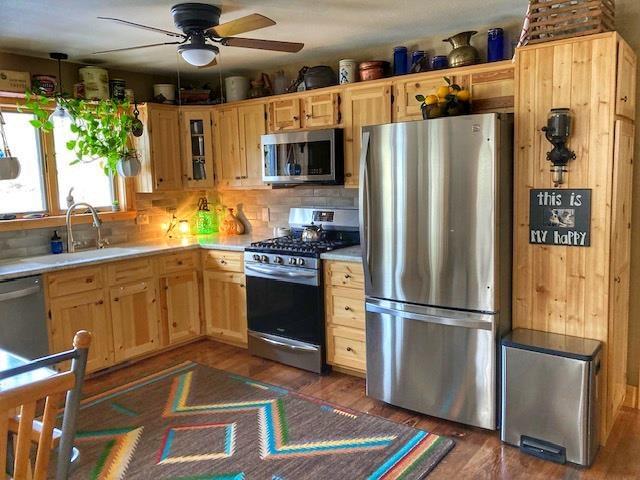 kitchen with a sink, stainless steel appliances, light countertops, and dark wood finished floors