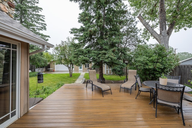 wooden terrace featuring outdoor dining area, a lawn, and fence