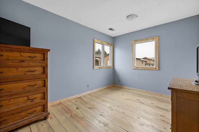 unfurnished bedroom featuring light wood-style floors, visible vents, and baseboards