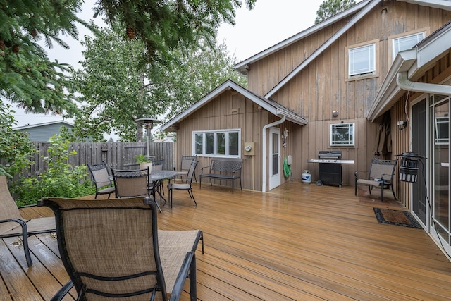 deck with outdoor dining area, area for grilling, and fence