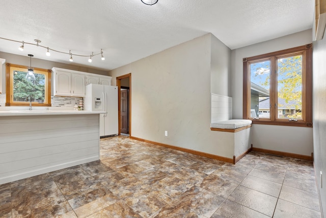 kitchen featuring white refrigerator with ice dispenser, white cabinets, light countertops, tasteful backsplash, and pendant lighting