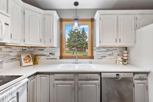 kitchen featuring white appliances, white cabinets, light countertops, pendant lighting, and a sink