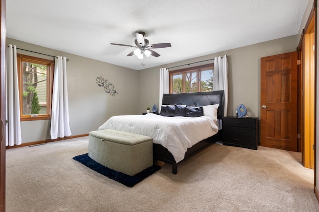 bedroom with light carpet, multiple windows, a ceiling fan, and baseboards