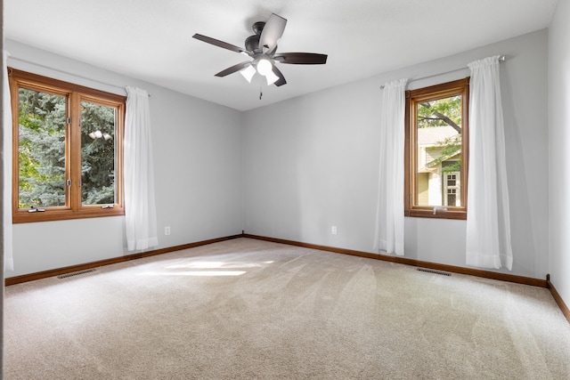 carpeted empty room featuring visible vents, ceiling fan, and baseboards