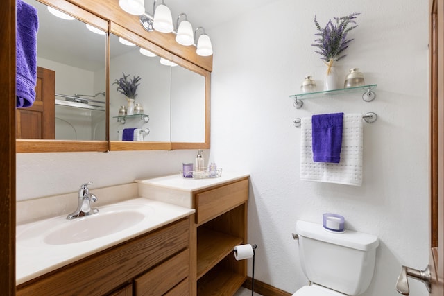 bathroom featuring toilet, a shower with shower door, and vanity