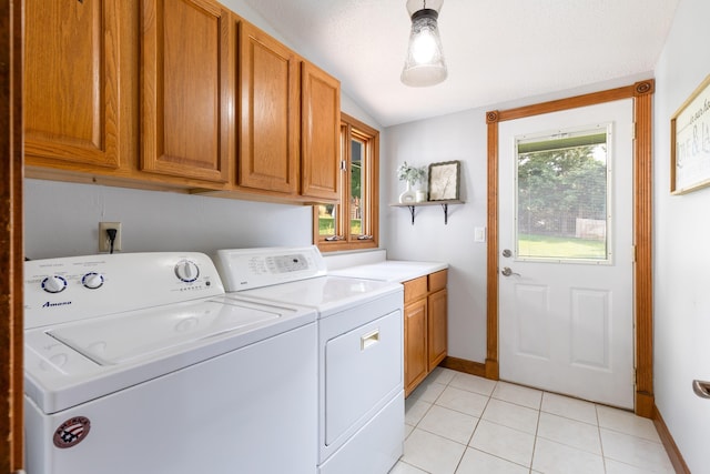 laundry area featuring cabinet space, light tile patterned floors, baseboards, and washing machine and clothes dryer