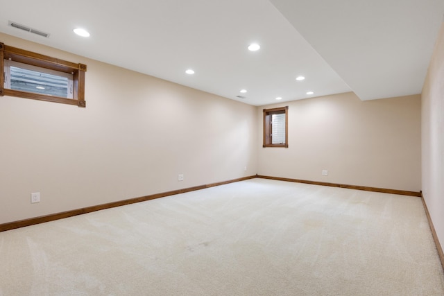 below grade area featuring light colored carpet, visible vents, baseboards, and recessed lighting