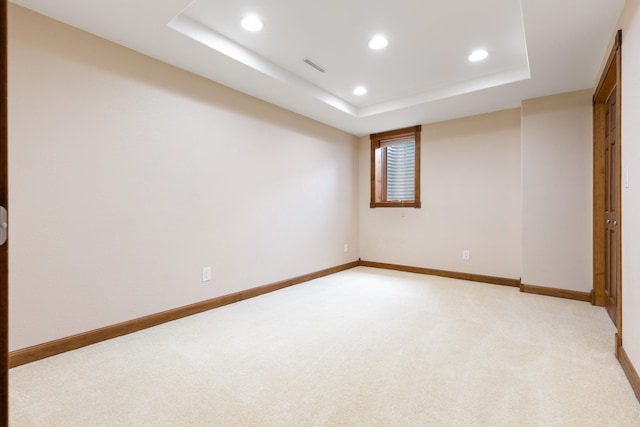 spare room featuring recessed lighting, a raised ceiling, and light carpet