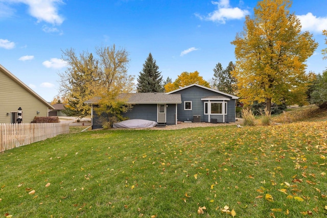 back of property with a lawn and fence