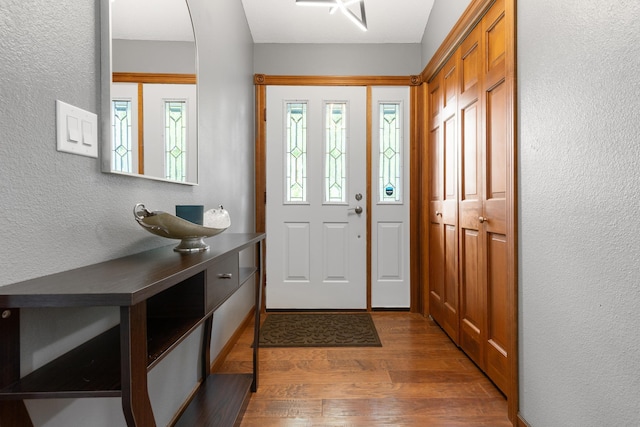 foyer entrance featuring dark wood-style floors, arched walkways, and a textured wall