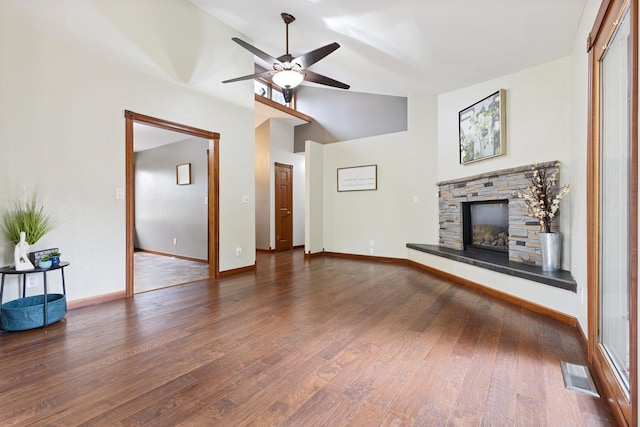 unfurnished living room with baseboards, visible vents, lofted ceiling, dark wood-style flooring, and a stone fireplace