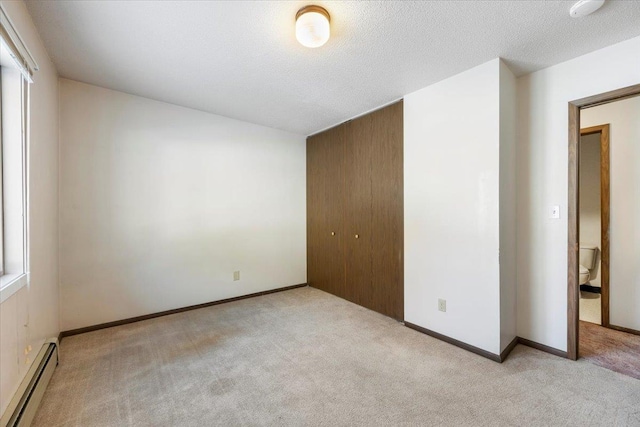 unfurnished bedroom featuring a baseboard heating unit, carpet, and a closet