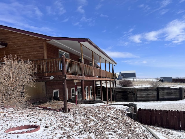 view of snowy exterior with fence and a balcony