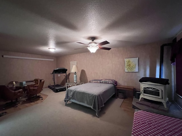 carpeted bedroom with a wood stove, ceiling fan, and a textured ceiling