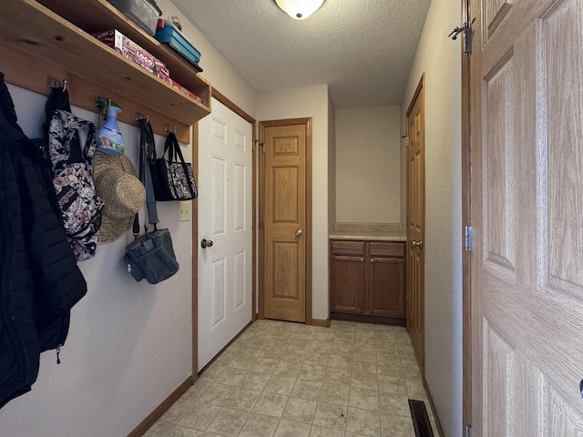 interior space featuring light floors, baseboards, and a textured ceiling