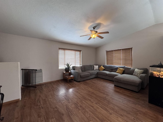 living area featuring dark wood finished floors, lofted ceiling, a ceiling fan, a textured ceiling, and baseboards