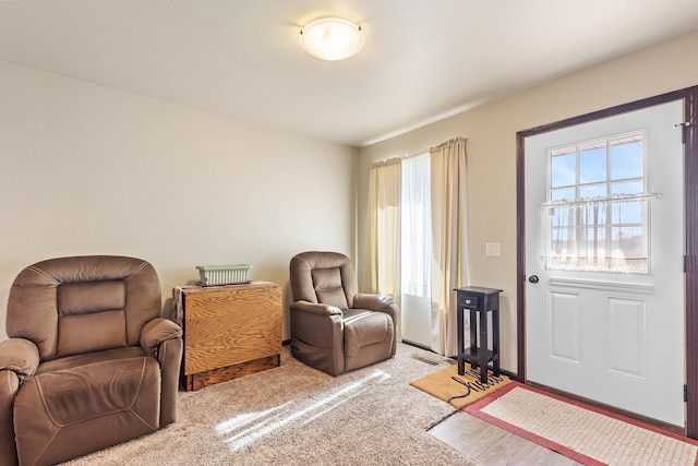 living area with carpet flooring, visible vents, and a healthy amount of sunlight