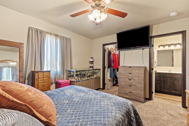 bedroom featuring light carpet, ensuite bath, ceiling fan, a sink, and a closet