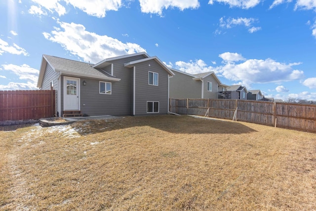 back of property featuring a fenced backyard and a lawn