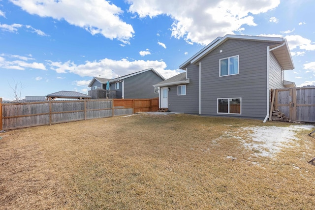 rear view of house with a fenced backyard and a lawn